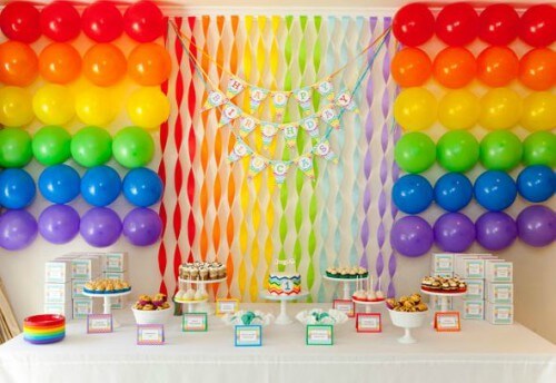 Mesa de doces decorada com balões e fitas coloridas