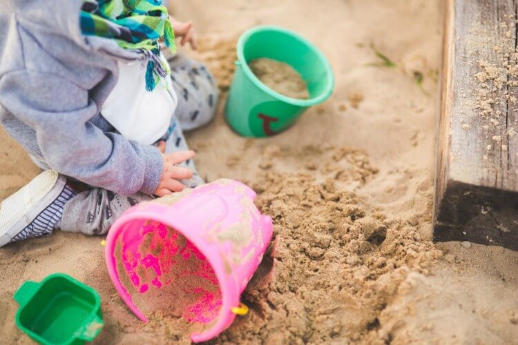 Criança brincando em tanque de areia de parquinho