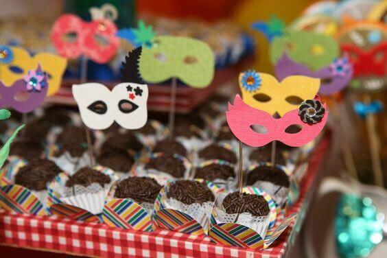 Mesa de docinhos em festa infantil decorada com máscaras de carnaval
