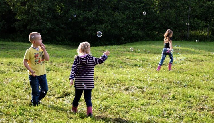 crianças brincando com bolhas no jardim