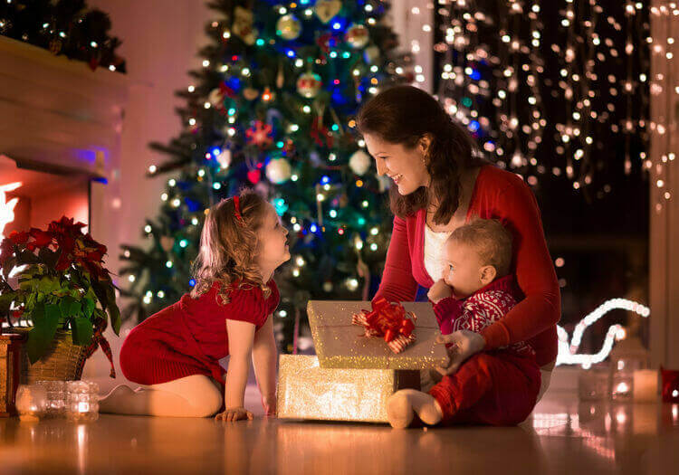 Mãe abrindo presentes de Natal com crianças