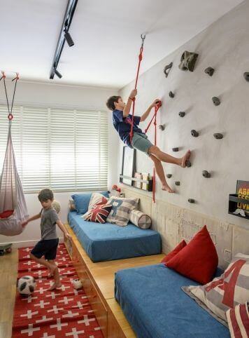 Menino brincando em parede de escalada em quarto infantil