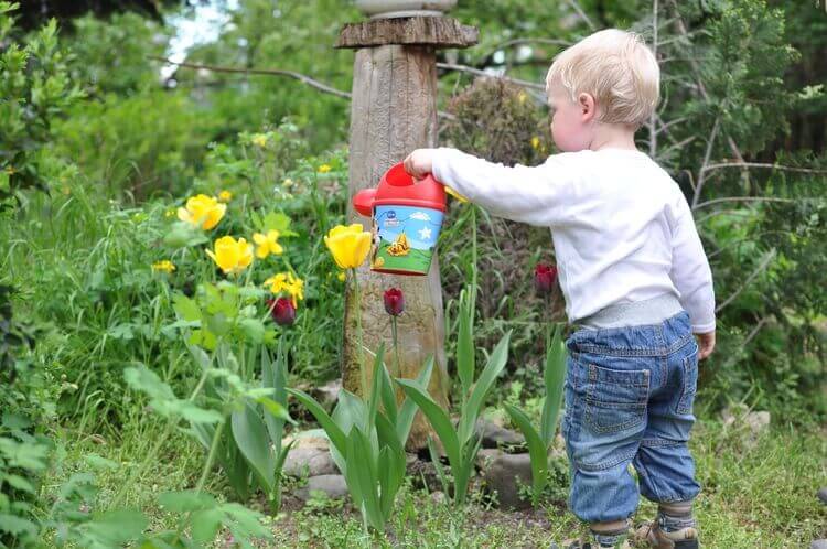 Bebê regando plantas em jardim
