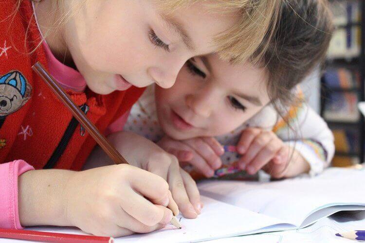 Crianças escrevendo em caderno escolar