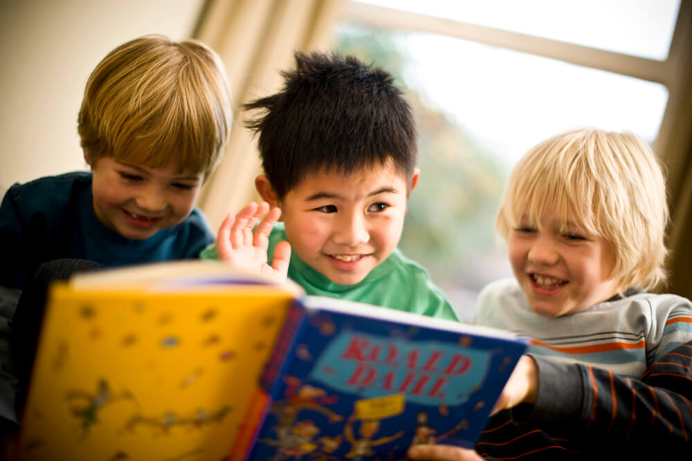 Crianças lendo livro em inglês.