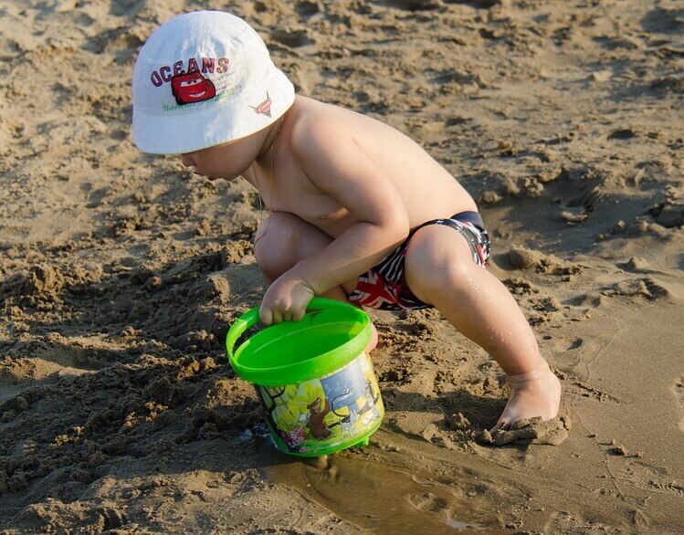 Criança brincando na areia da praia.